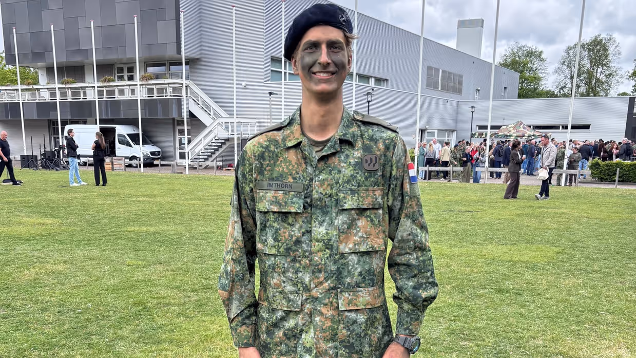 Een militair staat op een grasveld. 
