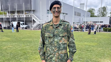Een militair staat op een grasveld. 