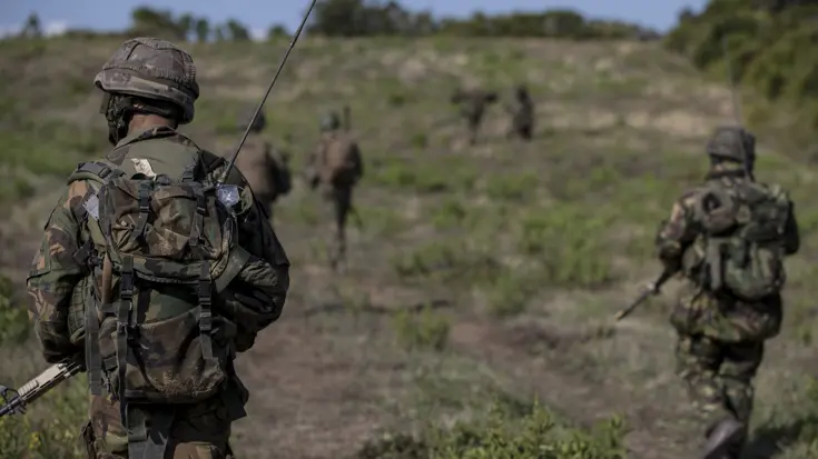 Militairen lopen door groen gebied.