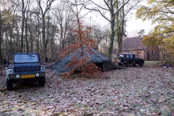 Legertent in bos met aan beide kanten een jeep.