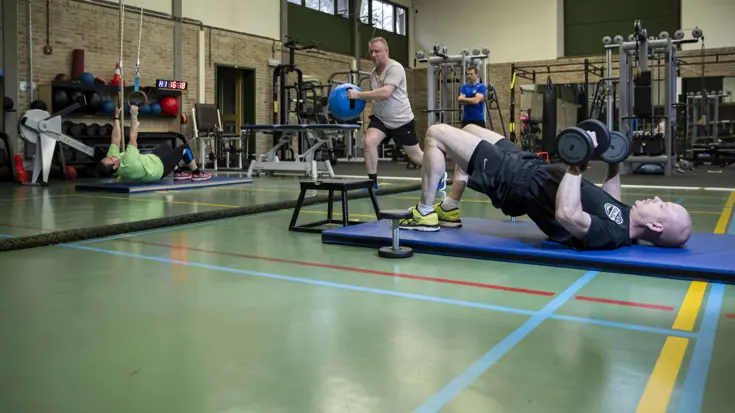 4 personen aan het sporten in een gymzaal.