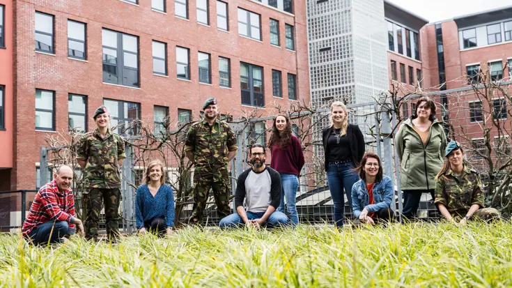 Een groep mensen poseren voor de foto met als achtergrond een gebouw.