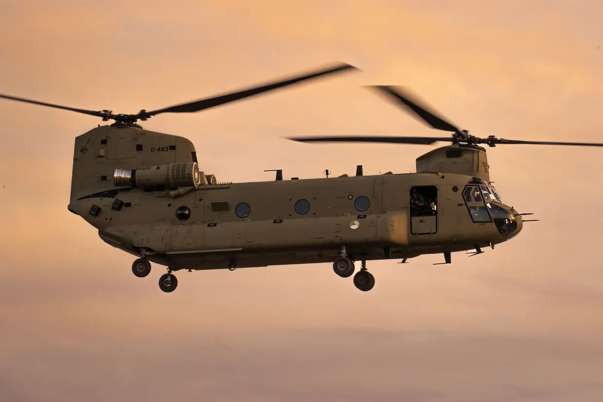 Een Chinook-transporthelikopter in een oranje gekleurde lucht.