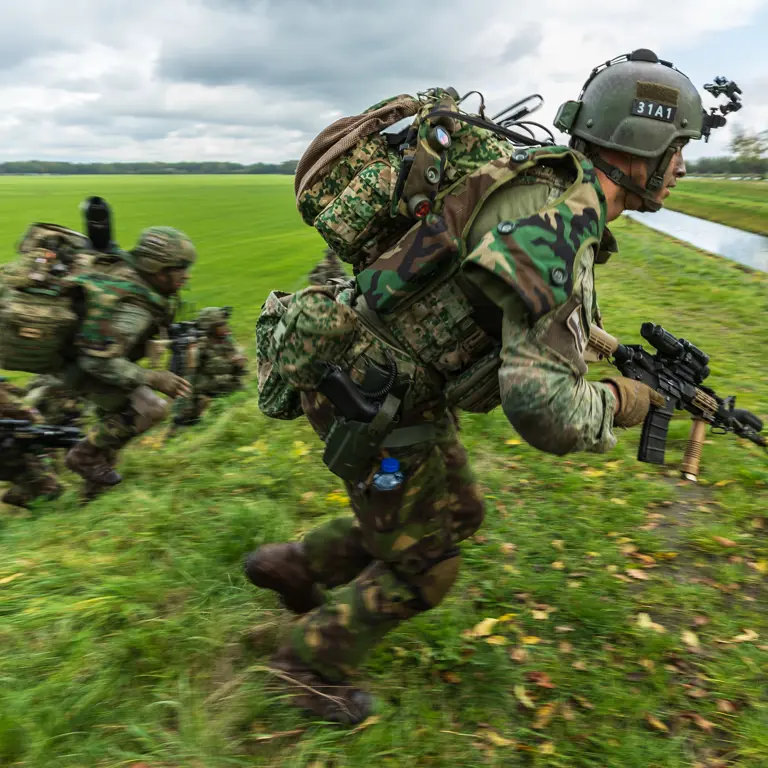 Militairen oefenen in een weiland.