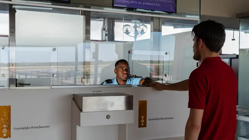 Een man overhandigt zijn paspoort aan een marechaussee.