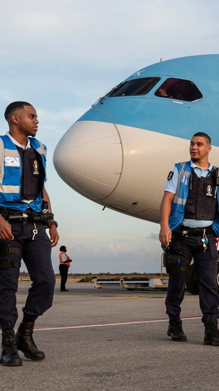 Marechaussees op het vliegveld op Bonaire met een vliegtuig van TUI op de achtergrond.