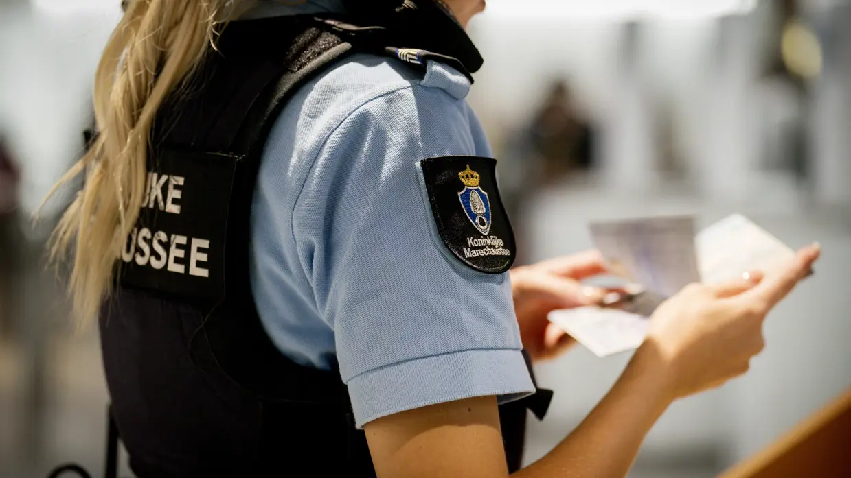 Vrouwelijke marechaussee controleert paspoort.