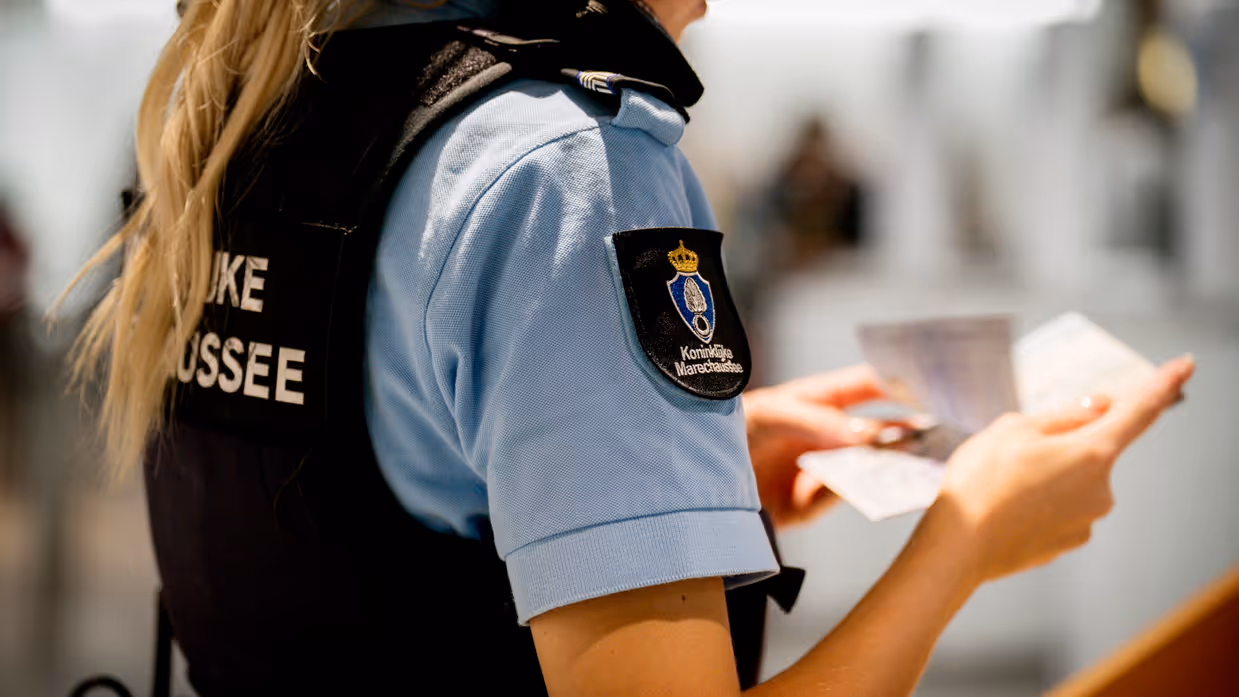Vrouwelijke marechaussee controleert paspoort.
