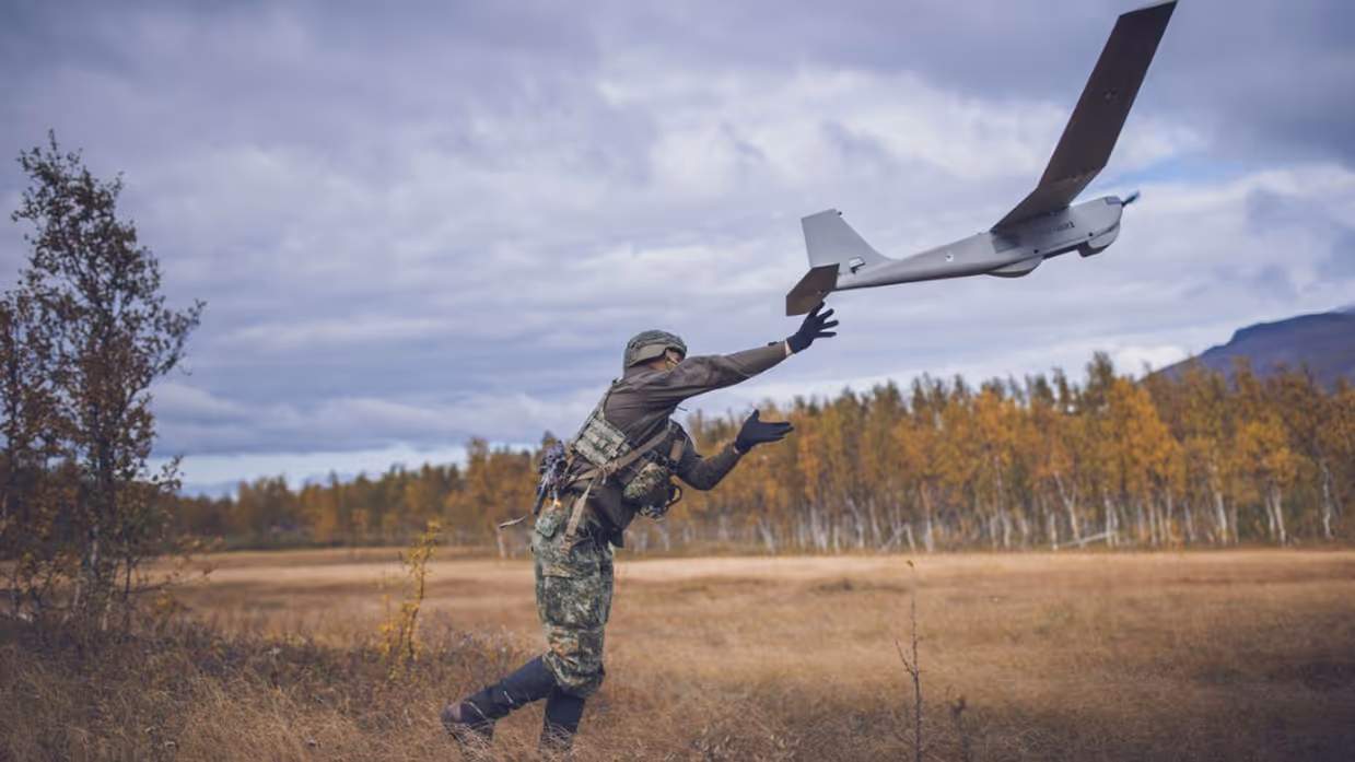 Een marinier lanceert een drone in de vorm van een klein vliegtuig met vaste vleugels.