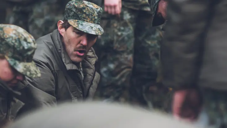 Militair met pet tussen collega's.
