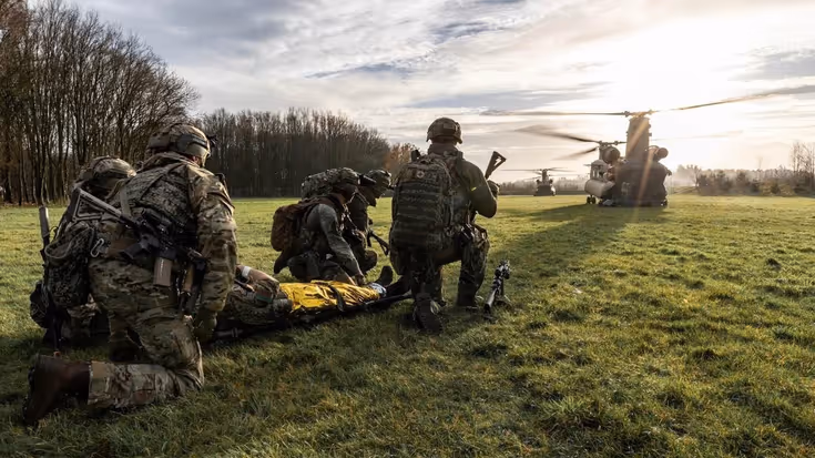 Militairen op de rug gezien, met daarachter een helikopter.