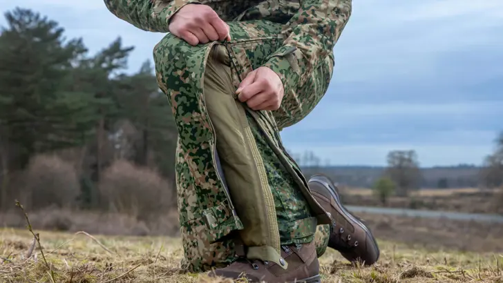 Militair toont kleding, ritst broekspijp open.