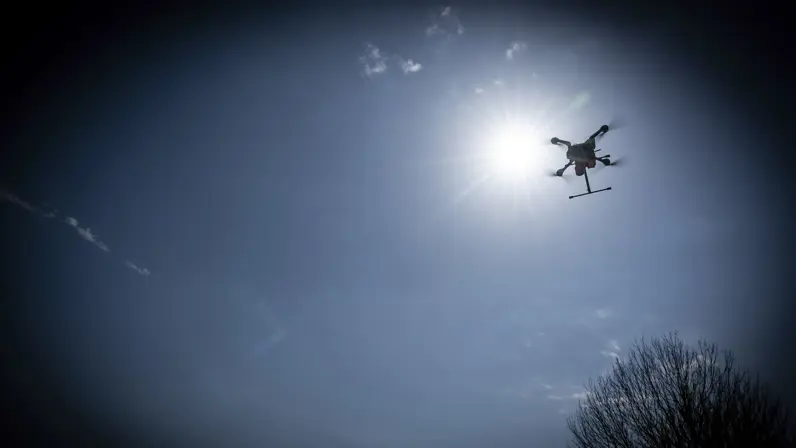 Een drone vliegt dreigend over aan een donkere hemel. 