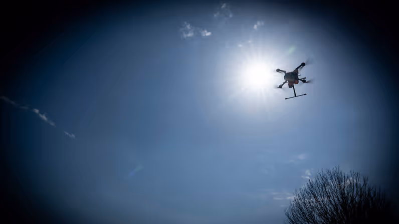 Een drone vliegt dreigend over aan een donkere hemel. 