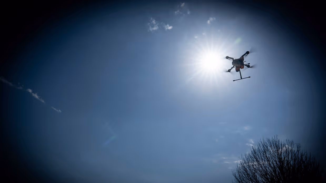 Een drone vliegt dreigend over aan een donkere hemel. 
