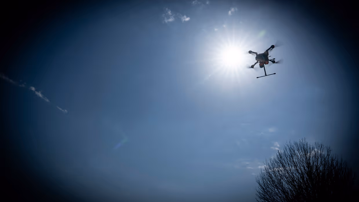 Een drone vliegt vlak voor de zon langs. De foto is bewerkt, waardoor er een zwarte rand rond het beeld is te zien.&nbsp;