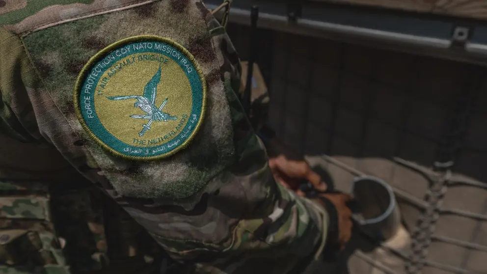 Logo van NAVO-missie op schouder van militair.