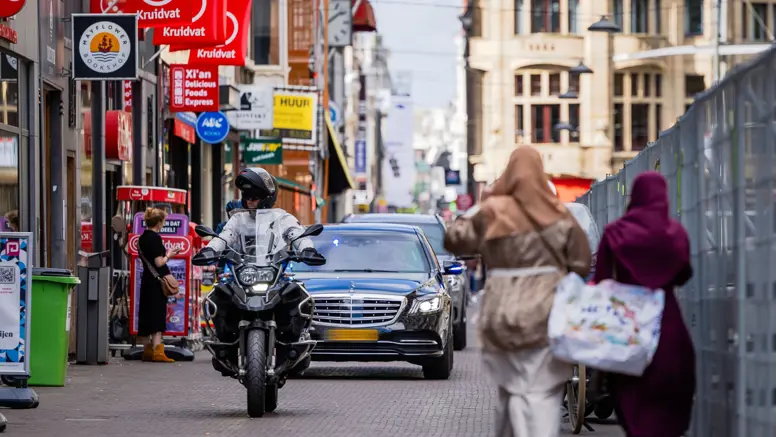 Twee auto’s met geblindeerde ramen rijden achter elkaar door een winkelstraat in Den Haag.