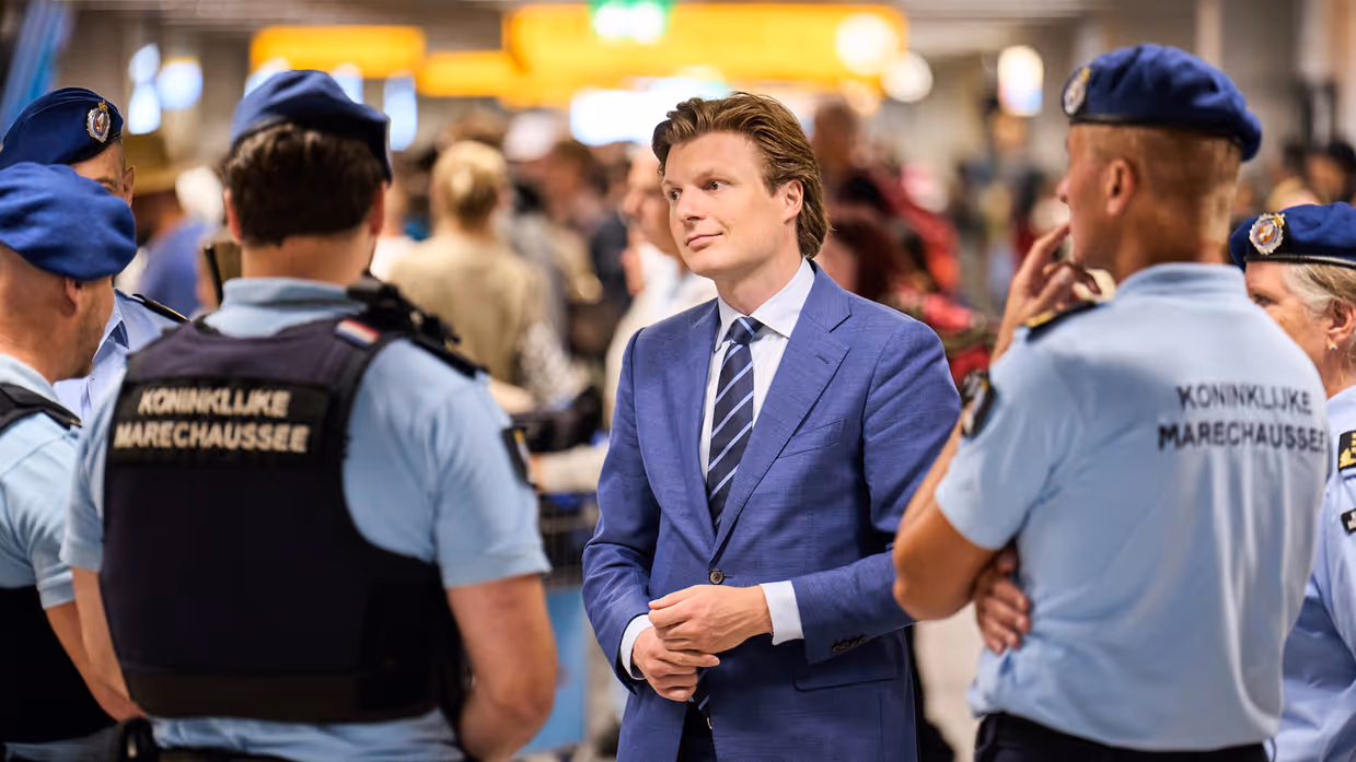  Staatssecretaris Tuinman praat met militairen in ME-tenue. Minister Brekelmans praat met een groepje marechaussees op Schiphol.