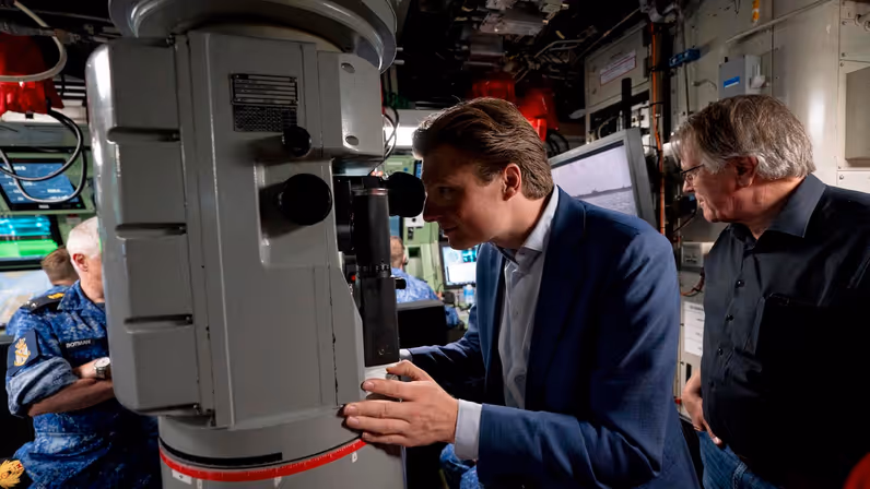 Minister Brekelmans kijkt door een periscoop.&nbsp;