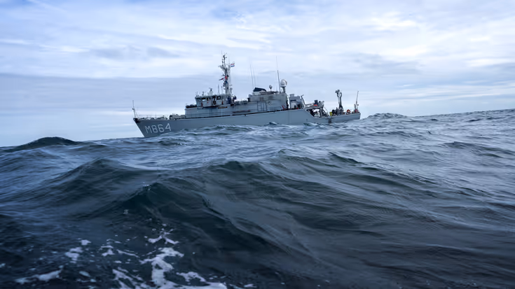 Marineschip vaart door woeste golven.