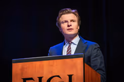 Minister Brekelmans geeft toespraak vanachter katheder.