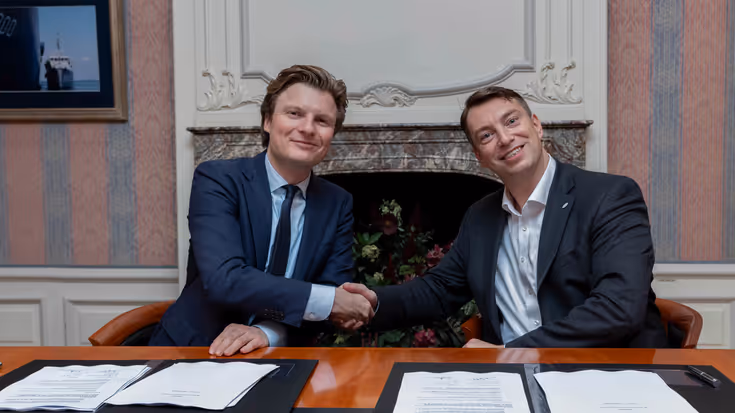 Minister Ruben Brekelmans (links) en ISISpace-CEO Jeroen Rotteveel (rechts) geven elkaar zittend achter een tafel een hand.