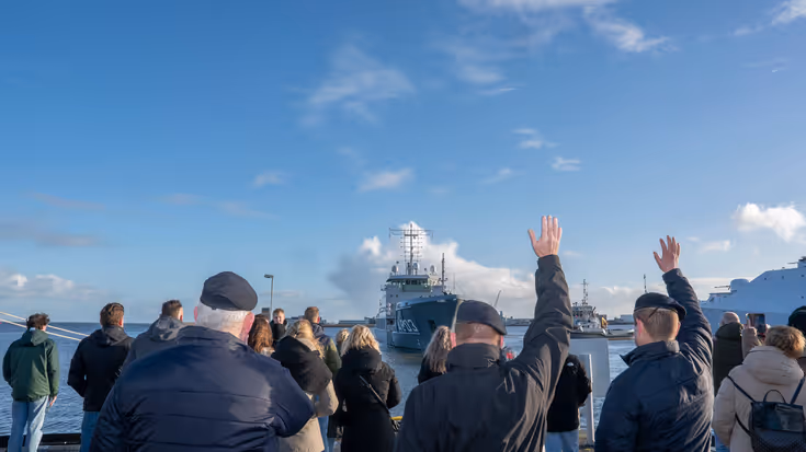 Mensen zwaaien een marineschip uit.