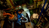 Monteur bezig met onderhoud in schip.