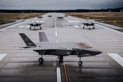 7 F-35's staan op een landingsbaan. De voorste is zichtbaar vanaf de zijkant. Van de overige 6 is de neus te zien.