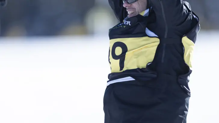 Een skiër juicht met beide armen omhoog.