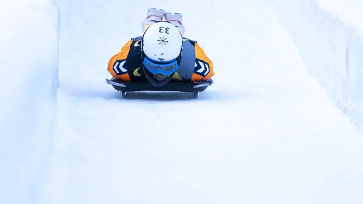 Een persoon glijdt op het ijs tijdens de skeleton-wedstrijd.
