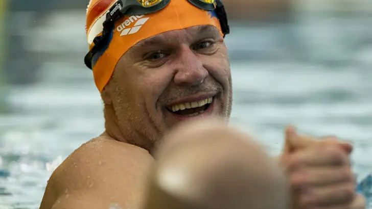 2 zwemmers in het water geven elkaar een hand.