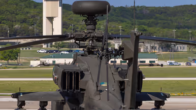 De achterkant van een Apache op een platform die met zijn neus gericht is naar de luchtverkeerstoren iets verderop.