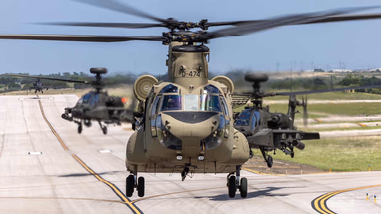 Een Chinook taxiet naar de startbaan. Daar valk achter twee Apaches.