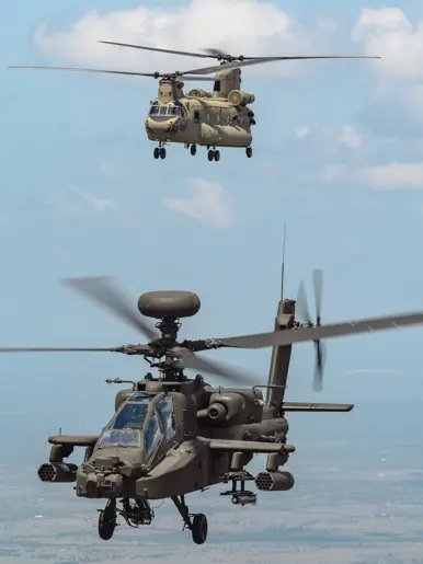 Een vliegende Chinook en Apache tegen een blauwe lucht met een enkel wolkje.