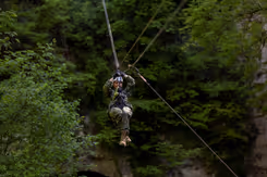 Militair daalt tussen de bomen af met een zipline.