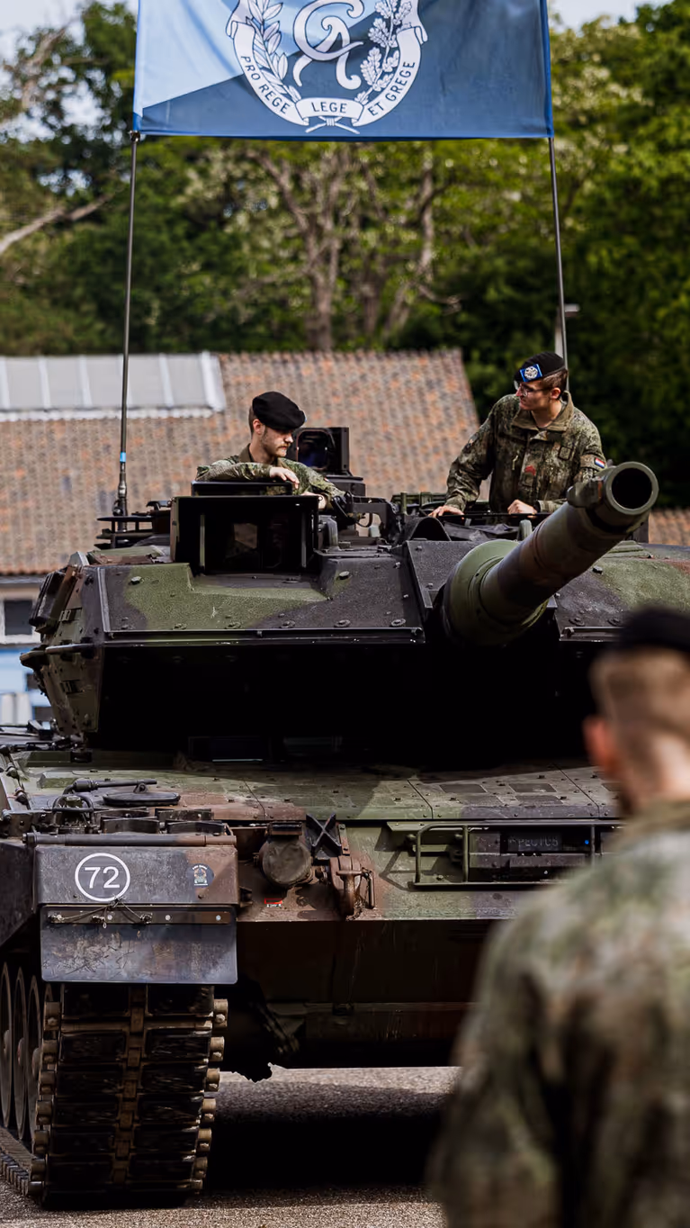 Militairen staan opgesteld voor een gevechtstank.  