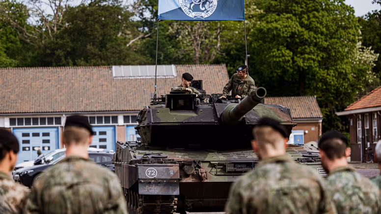 Militairen staan opgesteld voor een gevechtstank.  
