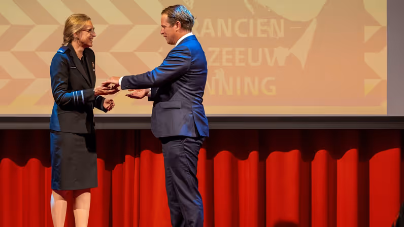  Boekholt-O’Sullivan staat op een podium en krijgt de prijs uit handen van voormalig staatssecretaris Gijs Tuinman.