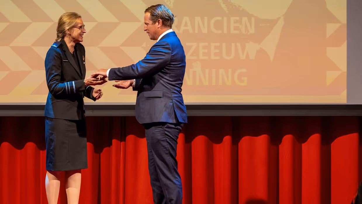  Boekholt-O’Sullivan staat op een podium en krijgt de prijs uit handen van voormalig staatssecretaris Gijs Tuinman.