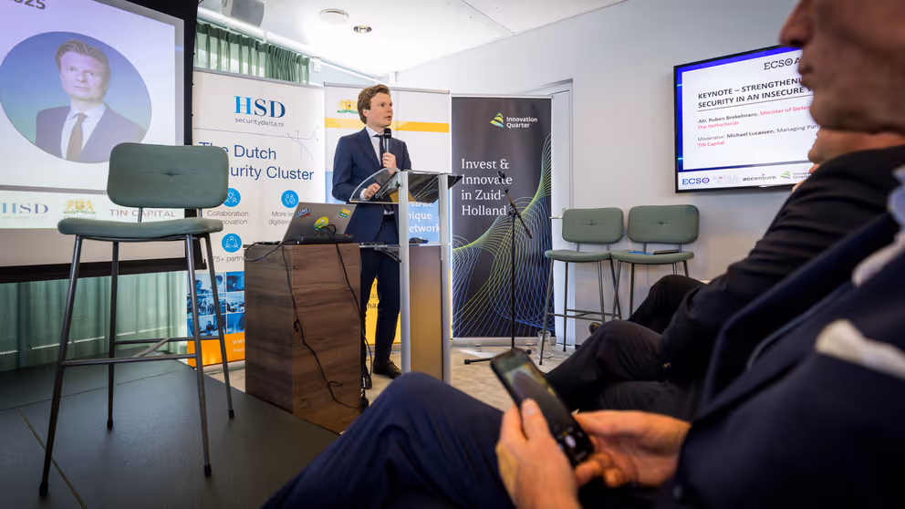 Minister Brekelmans tijdens speech achter katheder.