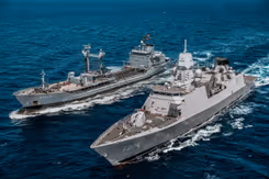 2 marineschepen naast elkaar op open water.