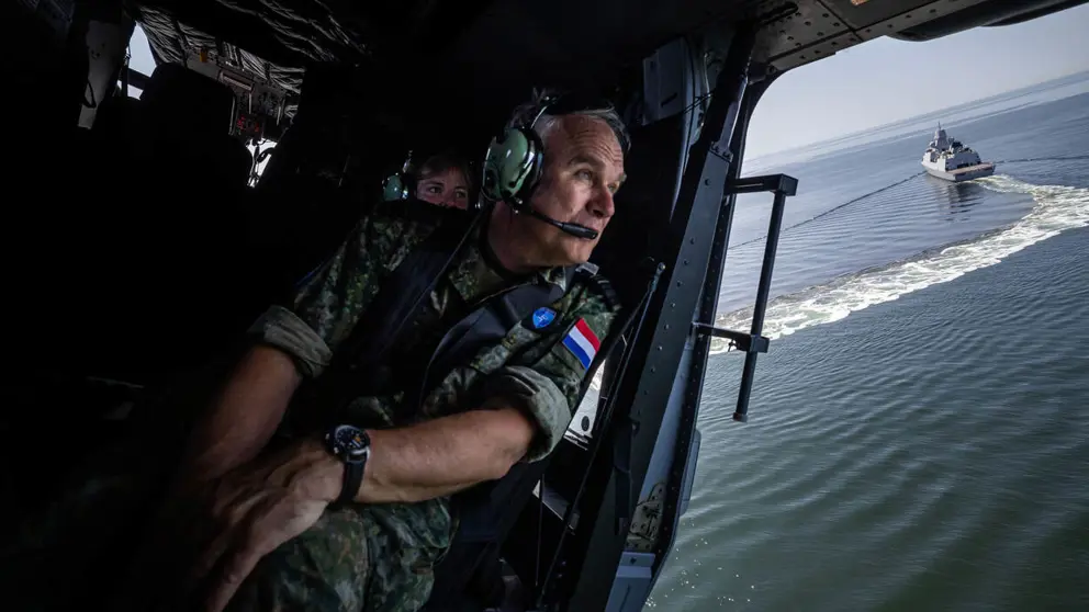 De commandant der Strijdkrachten in een helikopter boven zee. 