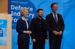 Een vrouw en twee mannen staan lachend naast elkaar op een podium.