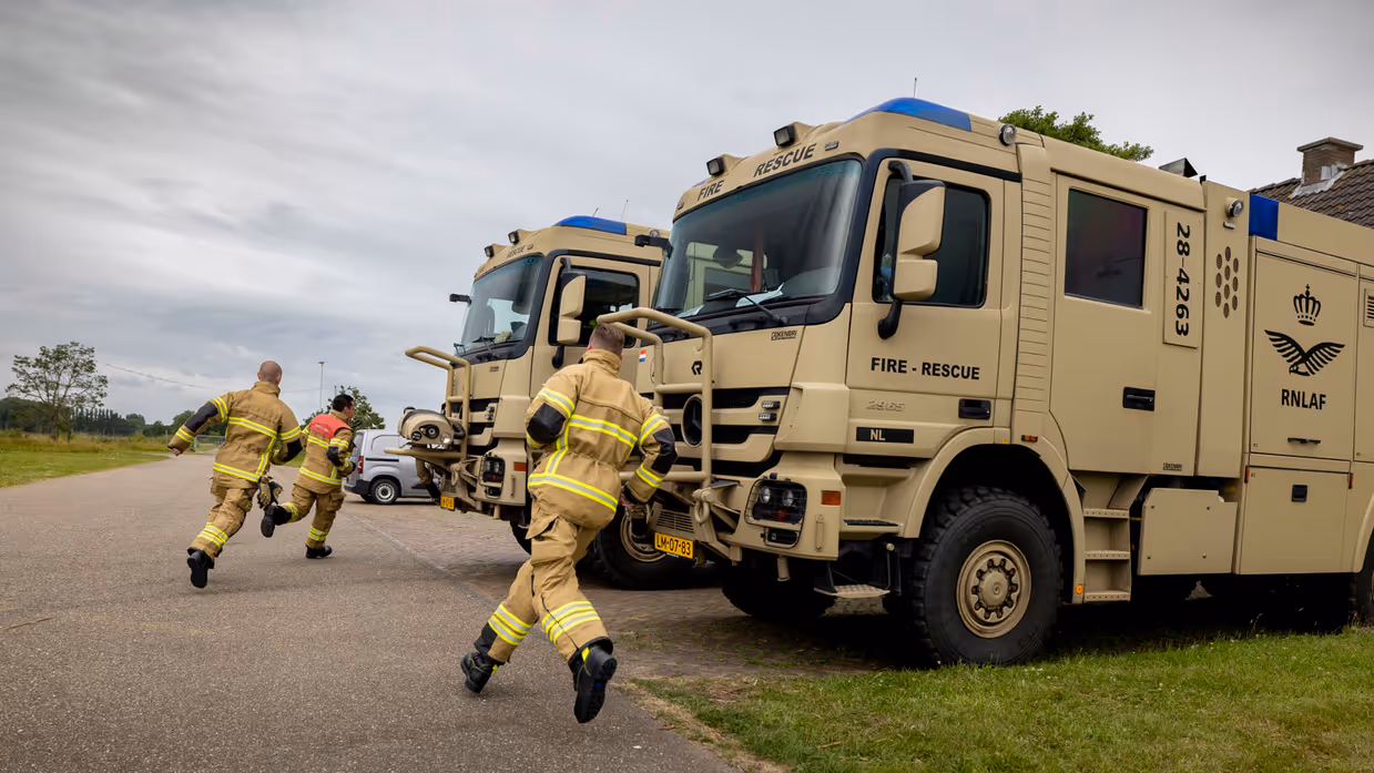 Militaire brandweermannen rennen over het platform naar hun wagens.