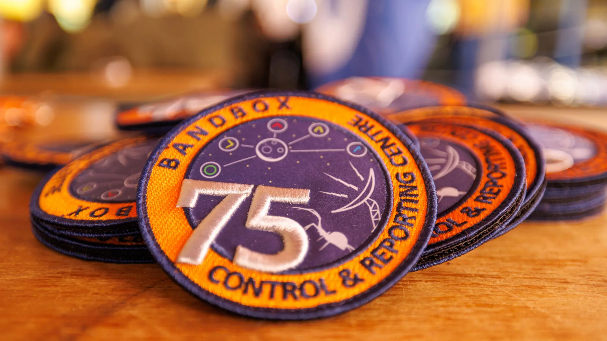 Een verzameling oranje-paarse badges met daarop het getal 75 en de teksten Bandbox en Control & Reporting Centre.