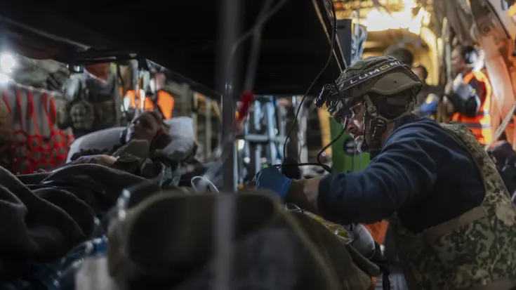 Twee gewonde militairen op brancards in een helikopter. Een militair medicus behandelt een van de twee.