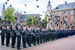 Officieren gooien hun pet in de lucht.