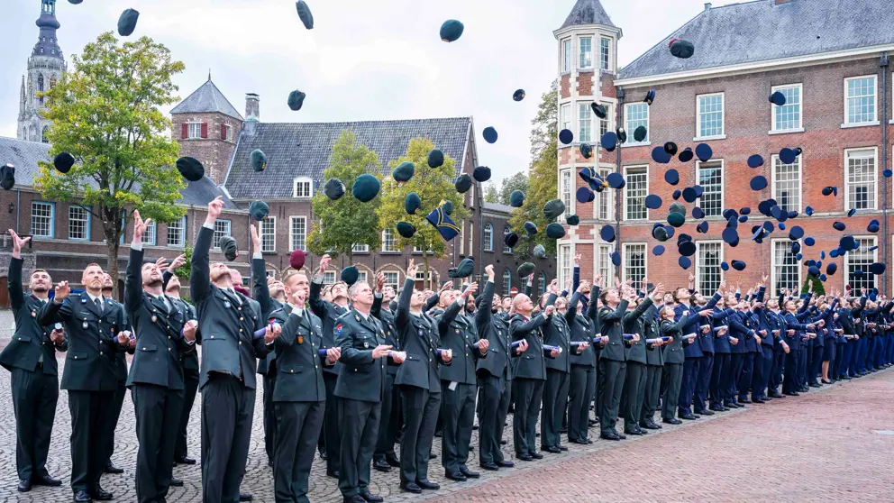 Officieren gooien hun pet in de lucht.